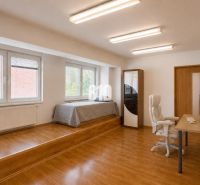 A spacious room in a 2-room apartment with a wooden decor floor and an office desk.
