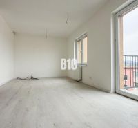 A bright living room with large windows and a wooden decor floor in a 2-room apartment.