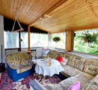 A veranda with sofas, flowers, and a wooden decor floor in Olešná.