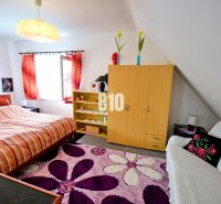 Interior of a cabin with a comfortable bed, colorful curtains, and a patterned carpet.
