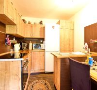 A kitchen in a cabin with wooden decor, equipped with appliances and storage space.