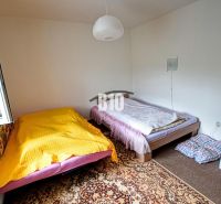 A room in a cottage with two beds, a white wall, and a carpet.