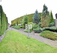 A landscaped garden of a family house in Súľov-Hradná with a path surrounded by greenery and ceramics.