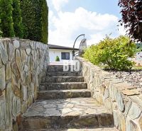Stone steps leading to a family house in Súľov-Hradná surrounded by greenery and stones.