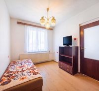 A room in a family house with a bed, a television, and a floor with a wooden decor.