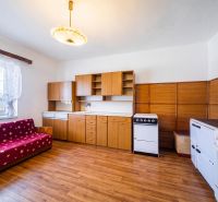 A kitchen in a family house with a kitchen unit, stove, and a floor with a wooden decor.