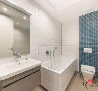 A bathroom of a 2-room apartment with a bathtub, sink, and toilet in white and blue tiles.