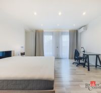 Bedroom in a two-room apartment with a wooden decor floor and a writing desk.