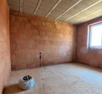 The interior of an unfinished room in a family house with a brick wall and a window.