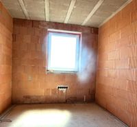 An unfinished room in a family house with construction bricks and a small window.