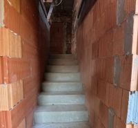 Unfinished staircase with raw brick walls in a family house.