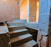 A staircase in an unfinished family house with brick walls and exposed wiring.