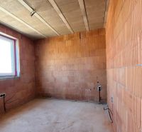 The interior of a family house with unfinished brick walls and a plastic window.