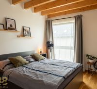 Bedroom with wood-patterned flooring, double bed, decorations, and an armchair in a 4-room apartment.