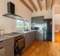 A kitchen in a 4-room apartment with a modern cooktop and flooring with a wood decor.