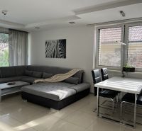 Living room of a family house with a corner sofa, a zebra poster, and a dining table.