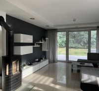 Living room in a family house with a fireplace, corner sofa, and large windows.