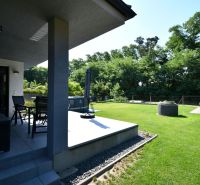 The garden of a family house in Šajdíkové Humence with a terrace and lawn surrounded by greenery.