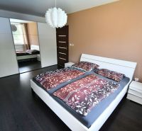 A bedroom in a family house with a dark floor, a large wardrobe, and a bed.