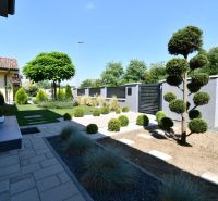 A garden at a family house in Šajdíkové Humence with landscaped greenery and paving.