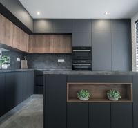 A kitchen in a family house with black furniture and wooden decor.
