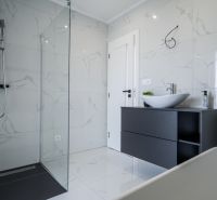 A bathroom in a family house with a glass shower enclosure and white ceramics.