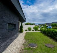 The exterior of a family house in Košúty with stone cladding and a garden.