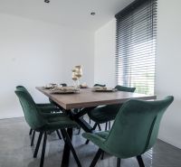A dining room with a wooden table and green chairs in a family house.