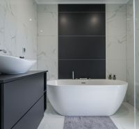 A bathroom in a family house with a bathtub, a sink, and tiles imitating marble.