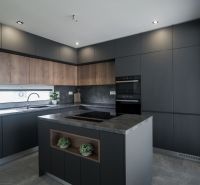 A kitchen with an island and a wooden decor floor in a family house.