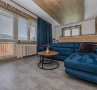 In the 3-room apartment, there is a blue sofa, a round table, and a floor with a wooden decor.