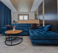 Blue sofa, wooden table, wooden decor flooring, brick, dark curtains.
