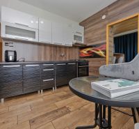 A kitchen in a 3-room apartment with light furniture and a wooden decor floor.