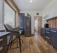 A kitchen in a 3-room apartment with a wooden decor floor and stylish furnishings.