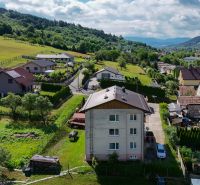 Aerial view of 3-room apartments in the village of Dohňany surrounded by greenery and mountains.