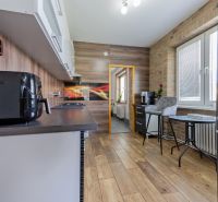 A kitchen in a 3-room apartment with a wooden decor floor and a dining table.