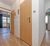 A hallway in a 3-room apartment with a wooden decor floor and an entrance to the kitchen.