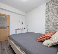 A bedroom in a 3-room apartment with a stone wall and a wooden decor floor.