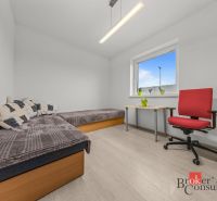 Bedroom in a family house with two beds, a table, and a red armchair.