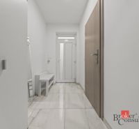 A hallway in a family house with white walls and a shiny floor.