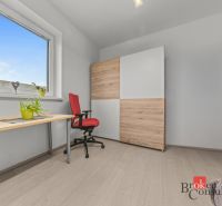 A minimalist room with a desk, a red chair, and a cabinet with a wooden decor.