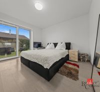 A bedroom in a family house with a French window and a floor with a wooden decor.
