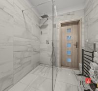 A bathroom in a family house with large-format tiles and a shower corner.