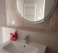 A bathroom with a sink and a round mirror in a 2-room apartment.