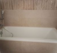 A bathroom with a bathtub and tiles in a 2-room apartment.