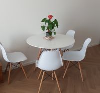 A round table with white chairs on a wooden floor in a 2-room apartment.