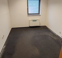 Interior of an office with a window, radiator, and dark-colored flooring.