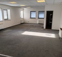 Offices with windows and carpet, bright walls and ceiling lighting.