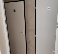 Toilets in commercial premises with white doors and a neutral wall.