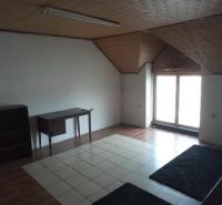 The interior of a building with tiled flooring, a writing desk, and a window, with a carpet on the floor.
